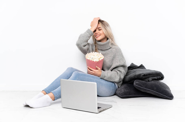Teini blondi tyttö syö popcornia katsellessaan elokuvaa kannettavalla tietokoneella on tajunnut jotain ja aikoo ratkaisun. - Valokuva, kuva