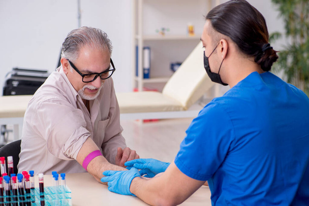 Paciente idoso visitando jovem médico masculino em transfusão de sangue conc - Foto, Imagem