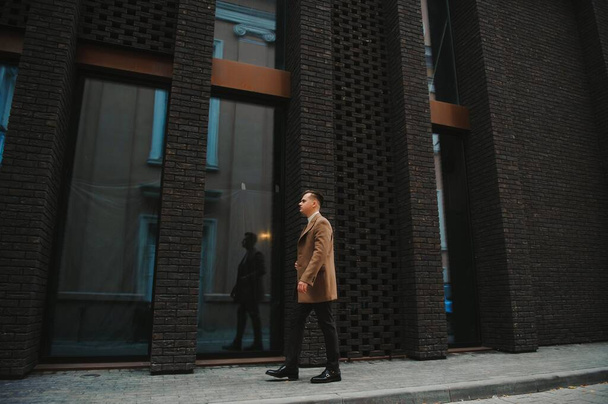 Portrait of handsome fashion businessman model dressed in elegant suit. Man posing on street background. Metrosexual - 写真・画像