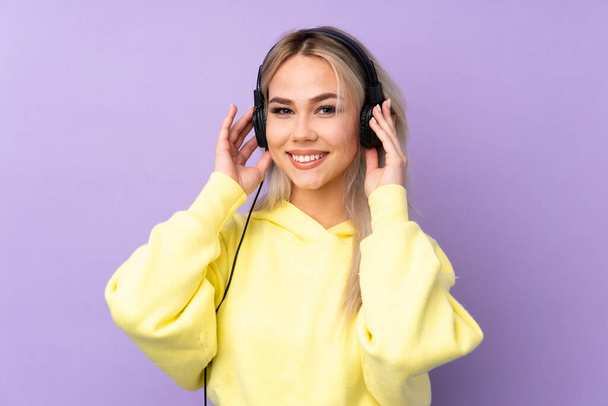 Adolescente chica sobre aislado púrpura fondo escuchar música - Foto, Imagen