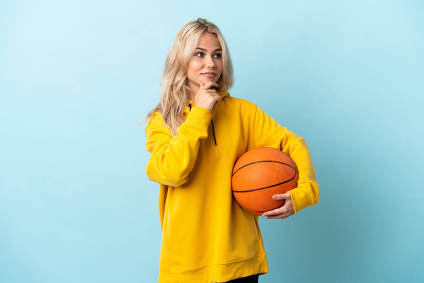 Young Russian woman playing basketball isolated on blue background thinking an idea while looking up - Foto, Imagen
