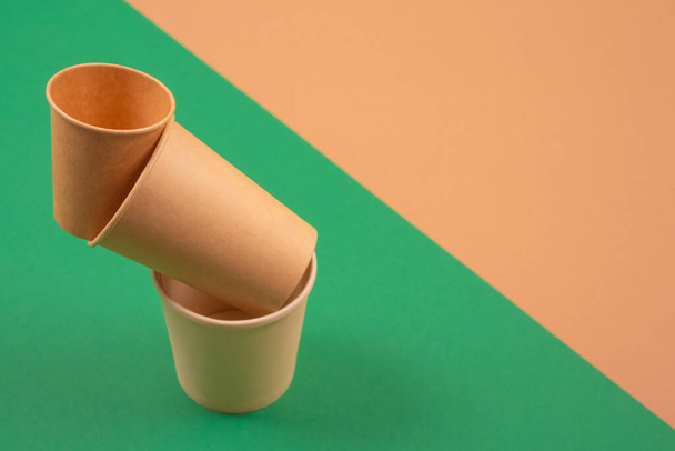 Set of balancing bioderadable takeaway beverages cups - kraft paper coffee cups on green and brown background with copyspace. Recycled kraft paper tableware or zero waste concept, mockup image - Foto, afbeelding