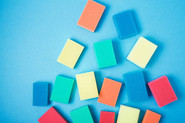 Mavi arka planda bulaşık yıkamak için yeni renkli süngerler - Fotoğraf, Görsel