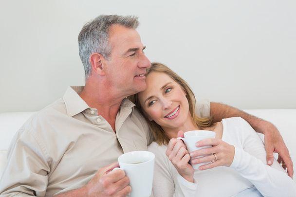 Relaxed loving couple with coffee cups in living room - Fotoğraf, Görsel