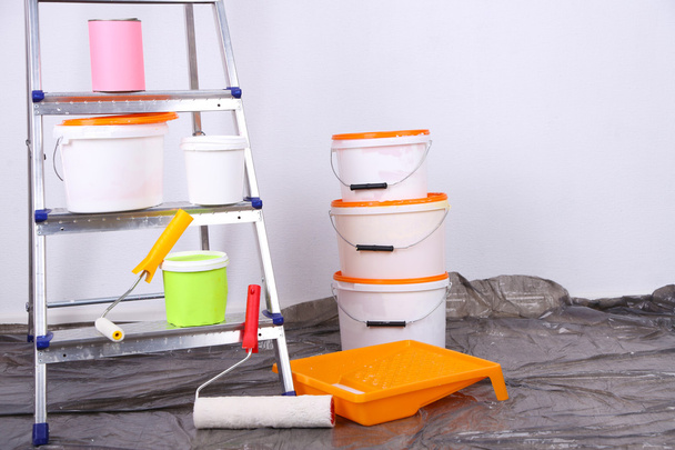 Buckets with paint and ladder on wall background. Conceptual photo of repairing works in  room  - Фото, зображення