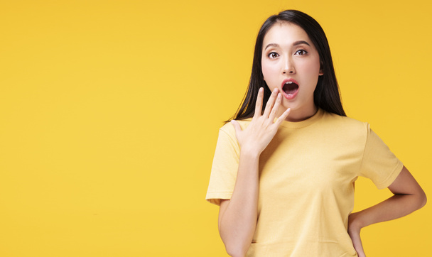 Έκπληξη και ενθουσιασμός έννοια. Νεαρή γυναίκα καλύπτει το στόμα της έκπληκτος ενθουσιασμένος, ενώ κοιτάζοντας το προϊόν στην πώληση προώθηση ή κενό χώρο αντίγραφο πάνω από απομονωμένο κίτρινο φόντο. - Φωτογραφία, εικόνα