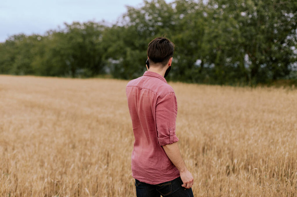 Фермер або агроном, що стоїть на полі пшениці, вивчаючи якість врожаю, говорячи на своєму смартфоні
 - Фото, зображення