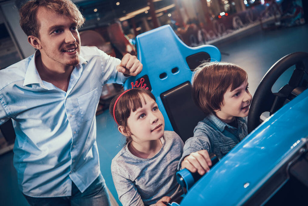 Dad watches his daughter and son drive a toy car. - Foto, Bild