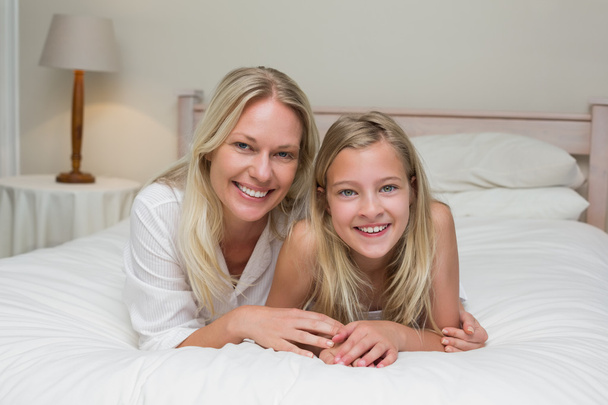 Woman with daughter lying in bed at home - Foto, Imagen