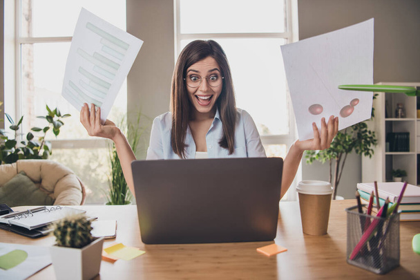 Photo of excited shocked girl sit desk hold documents look screen laptop wear specs shirt in home office indoors - Foto, Bild