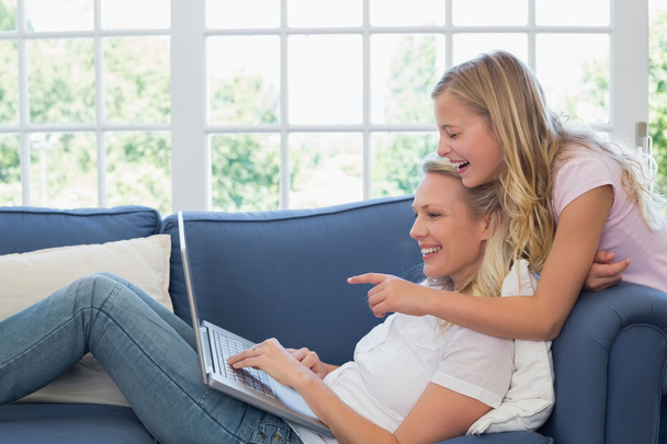 Girl pointing at laptop while mother using it - 写真・画像