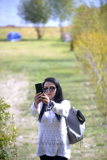 black hair model with smartphone, portrait in nature. - Zdjęcie, obraz