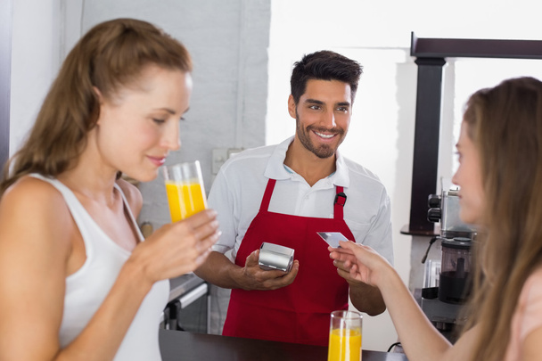 Women paying bill while drinking orange juice at coffee shop - Fotografie, Obrázek