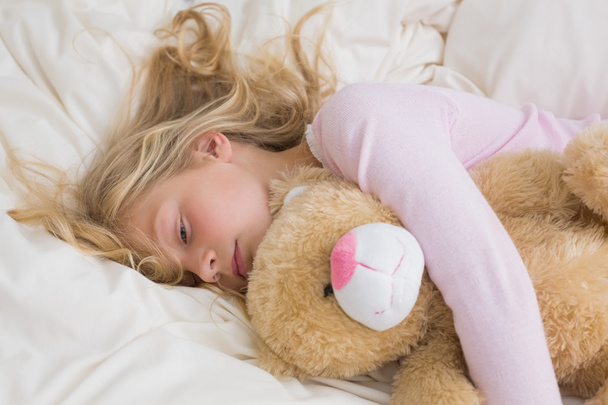 Girl sleeping peacefully with stuffed toy in bed - Fotó, kép