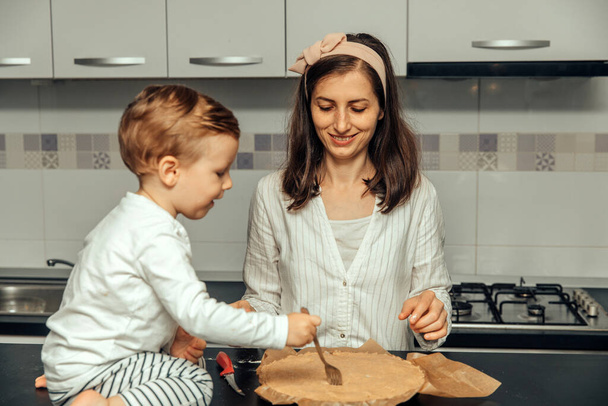 Mère et son garçon font une tarte aux pommes dans leur cuisine maison. - Photo, image