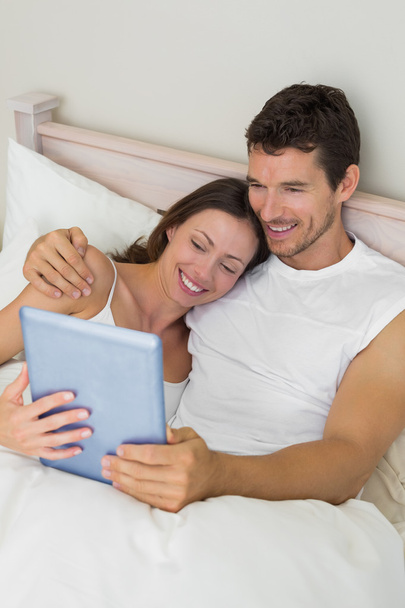 Happy couple using digital tablet in bed - Fotoğraf, Görsel