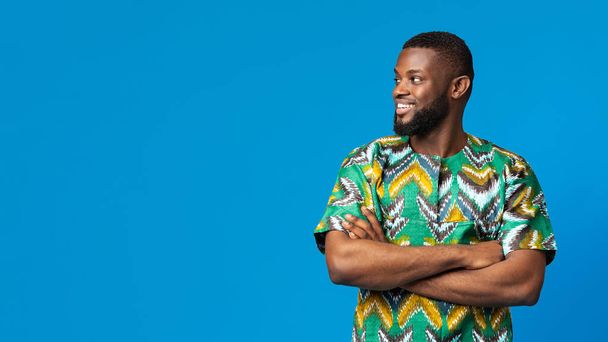 Komea musta kaveri afrikkalaisessa paidassa katselemassa kopiotilaa - Valokuva, kuva