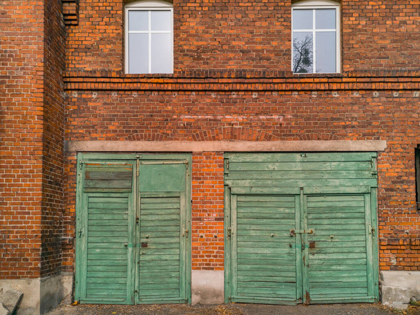 Dos puertas de madera verde para garajes en edificio de ladrillo rojo - Foto, Imagen