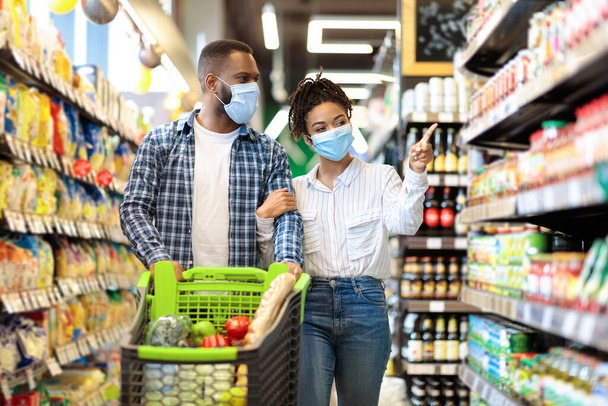 Африканська пара в захисних масках в супермаркеті робити продуктові магазини
 - Фото, зображення
