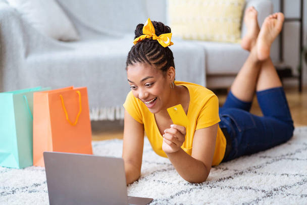 Fekete nő használja laptop és hitelkártya a padlón - Fotó, kép