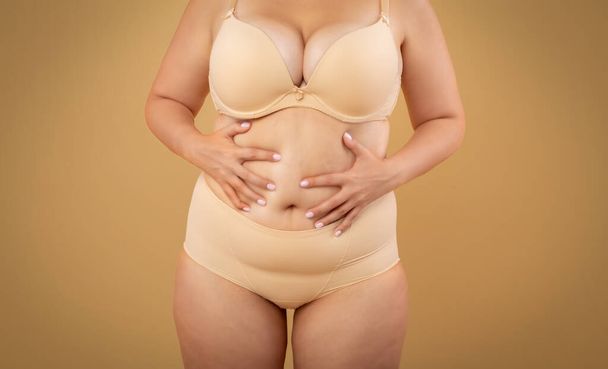 肥満と太りすぎ。ベージュの下着でプラスサイズの女性のトリミング肖像 - 写真・画像