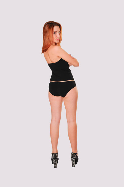 Back view of young red hair girl wearing black panties and corset - Fotó, kép
