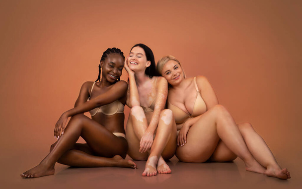 Gruppe von Frauen mit unterschiedlichen Körpertypen und Ethnien, die in Unterwäsche sitzen - Foto, Bild