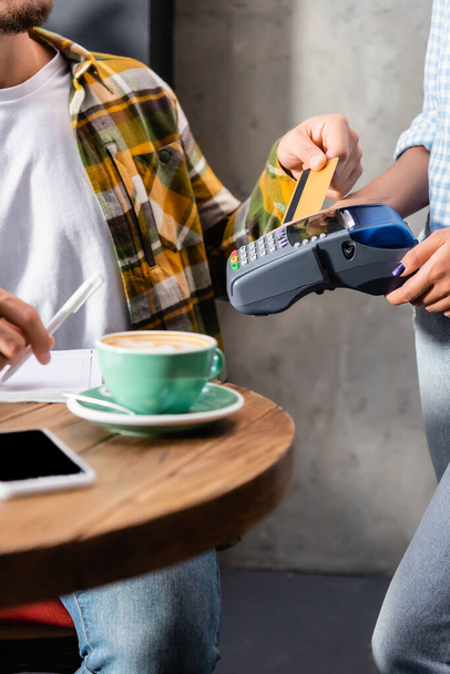 обрезанный вид официанта, держащего платежный терминал рядом с человеком с кредитной картой - Фото, изображение
