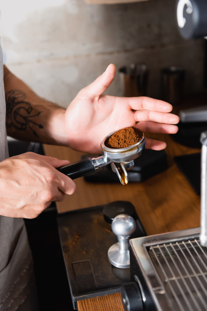 vista recortada de portafilter de tenencia de barista tatuado con café molido tostado - Foto, imagen