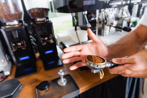 vue partielle de barista holding portafilter avec café moulu torréfié près de la cafetière - Photo, image