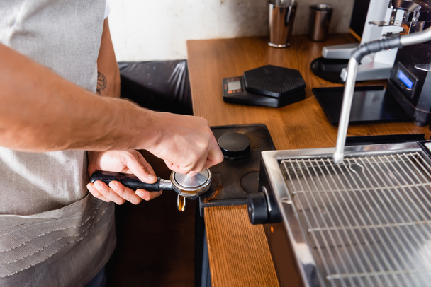 vista parcial de barista pressionando café em portafilter perto da máquina de café - Foto, Imagem