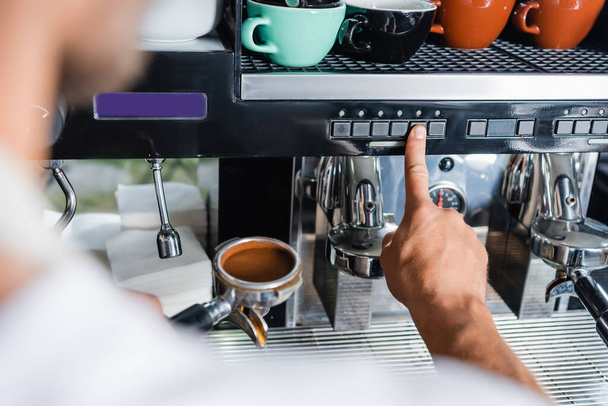 vista cortada de barista pressionando botão na máquina de café enquanto segurando portafilter, foreground borrado - Foto, Imagem