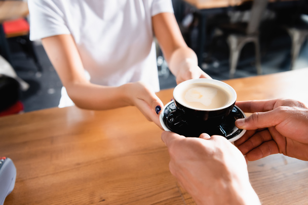 cropped view of man taking cup of coffee from barista on blurred background - Photo, Image