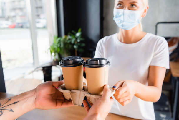 cropped view of barista giving takeaway coffee to woman in medical mask - Photo, Image