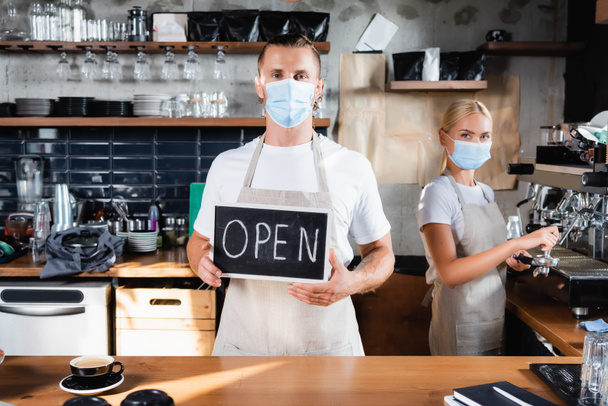 camarero en cartulina médica con letras abiertas cerca de barista trabajando sobre fondo - Foto, Imagen