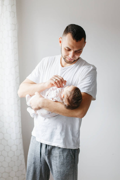 Young proud Caucasian father playing with newborn baby. Man parent holding rocking child daughter son on his hands. Authentic lifestyle candid moment. Family home life. Fathers Day. - Photo, Image