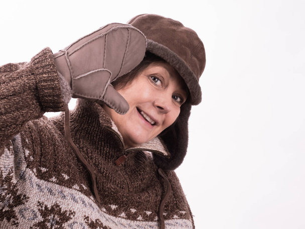 ウールのパターンセーター、冬の帽子で活動的な中年の女性は、波、挨拶や笑顔、優しい歓迎のジェスチャーを軽減します。隔離された白い背景、あなたのテキストの場所. - 写真・画像