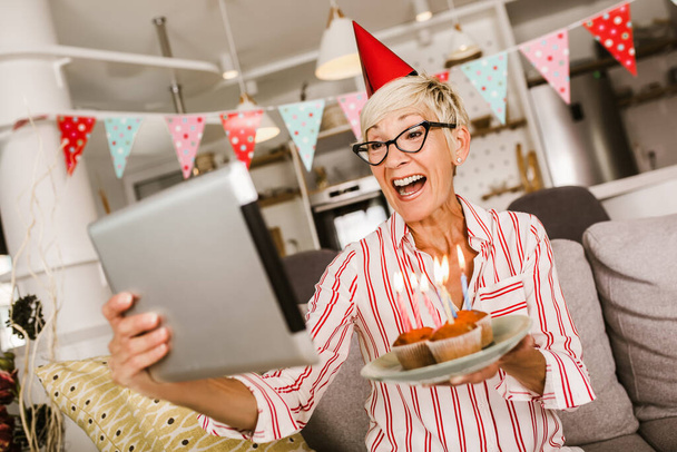 Mujer mayor sola en casa celebrando una videollamada - Foto, Imagen