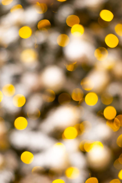 Colorful yellow Christmas Tree Bokeh background of de focused glittering lights. Pattern concept. Festive xmas bokeh defocused lights, close up. - Фото, изображение