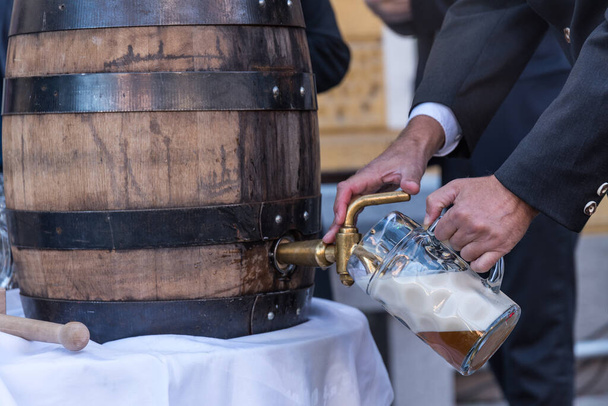 Деревянный бочонок пива при нажатии и наполнении первого пивного бокала - крупным планом - Фото, изображение