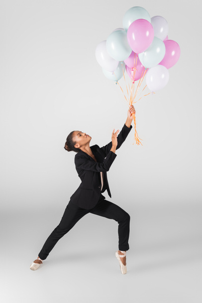 african american businesswoman performing ballet with balloons isolated on grey - Фото, зображення