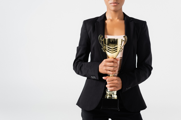 vista ritagliata di donna d'affari afro-americana con coppa d'oro isolata sul grigio - Foto, immagini
