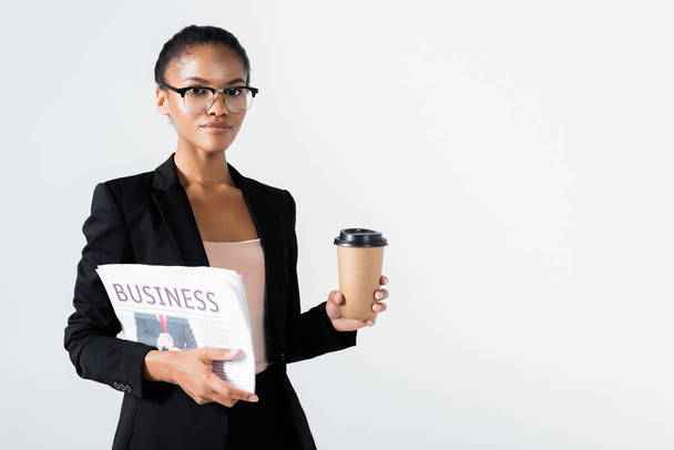 african american businesswoman with business newspaper and coffee to go isolated on grey - 写真・画像