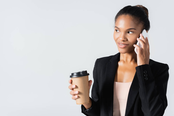 african american businesswoman with paper cup talking on smartphone isolated on grey - Fotografie, Obrázek