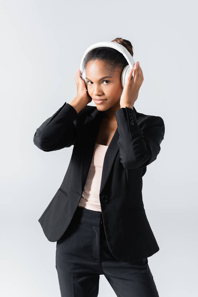 african american businesswoman listening music in headphones isolated on grey - Foto, Imagem