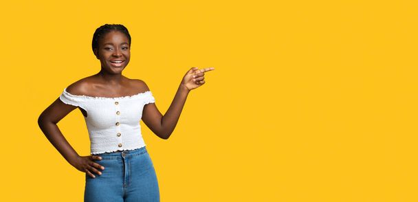 Check This. Cheerful Black Lady Pointing At Copy Space Over Yellow Background - Fotó, kép