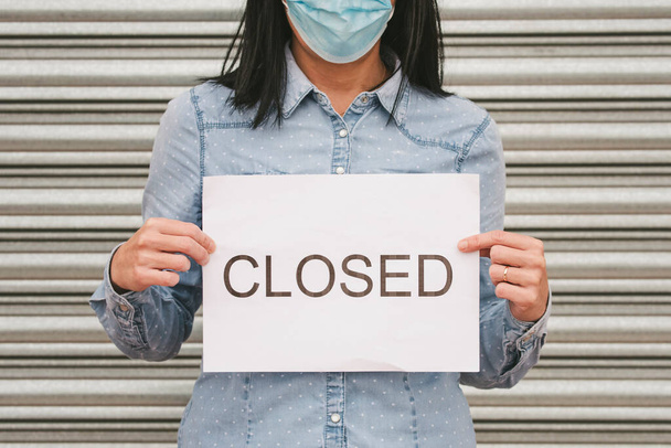 コロナウイルス。テキストが閉じて白い段ボールを保持している医療面マスクの女性。コロナウイルスのために店の閉鎖。選択的な焦点 - 写真・画像