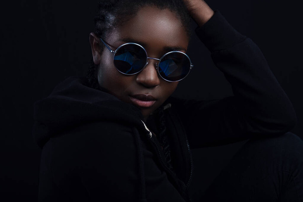 Close-up of cool woman with dark skin wearing round sunglasses - Foto, afbeelding