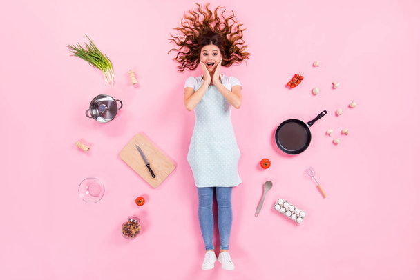 Full length high angle above flat lay view photo of pretty housewife lady lying floor arms on cheeks wear kitchen apron cooking ingredients utensils cuisine isolated pink color background - Photo, Image