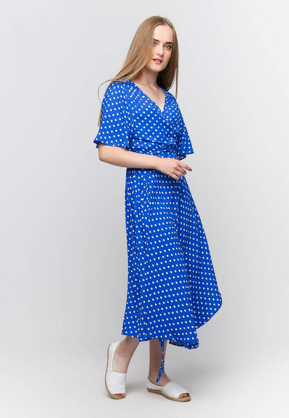 Açık mavi bir yaz elbisesi içinde, açık arkaplanda genç ve zarif bir kadın. Giyim mağazaları için reklam konsepti. Sosyal ağlar ve pankartlar için içerik. - Fotoğraf, Görsel
